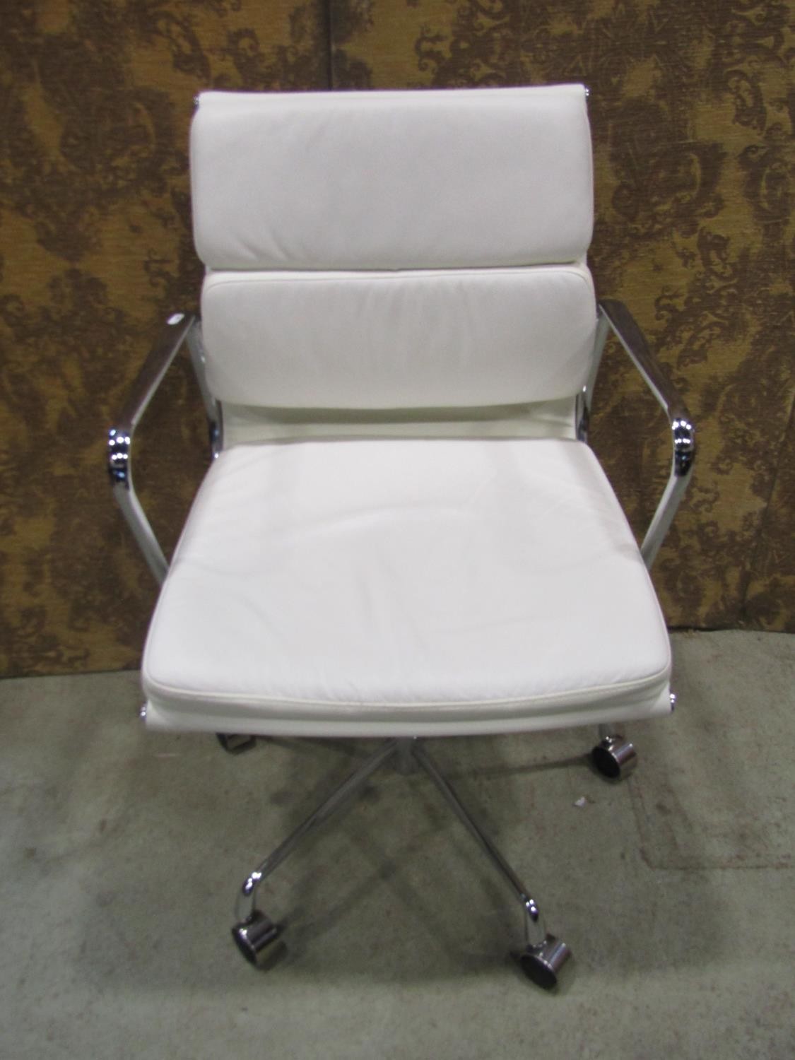 A contemporary chrome framed office chair with swivel base, upholstered in a faux white leather