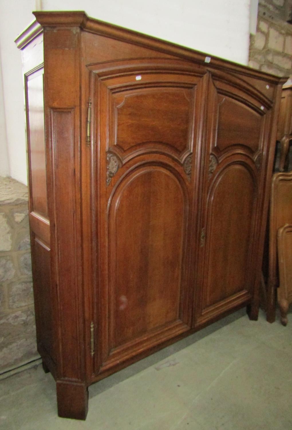 A low oak hanging hall wardrobe enclosed by a pair of carved and panelled doors, within a panelled