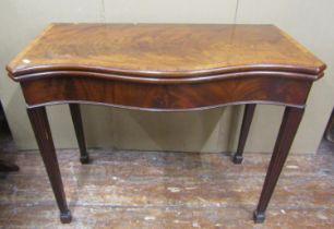 A Georgian mahogany serpentine fold over top card table on reeded and tapering supports