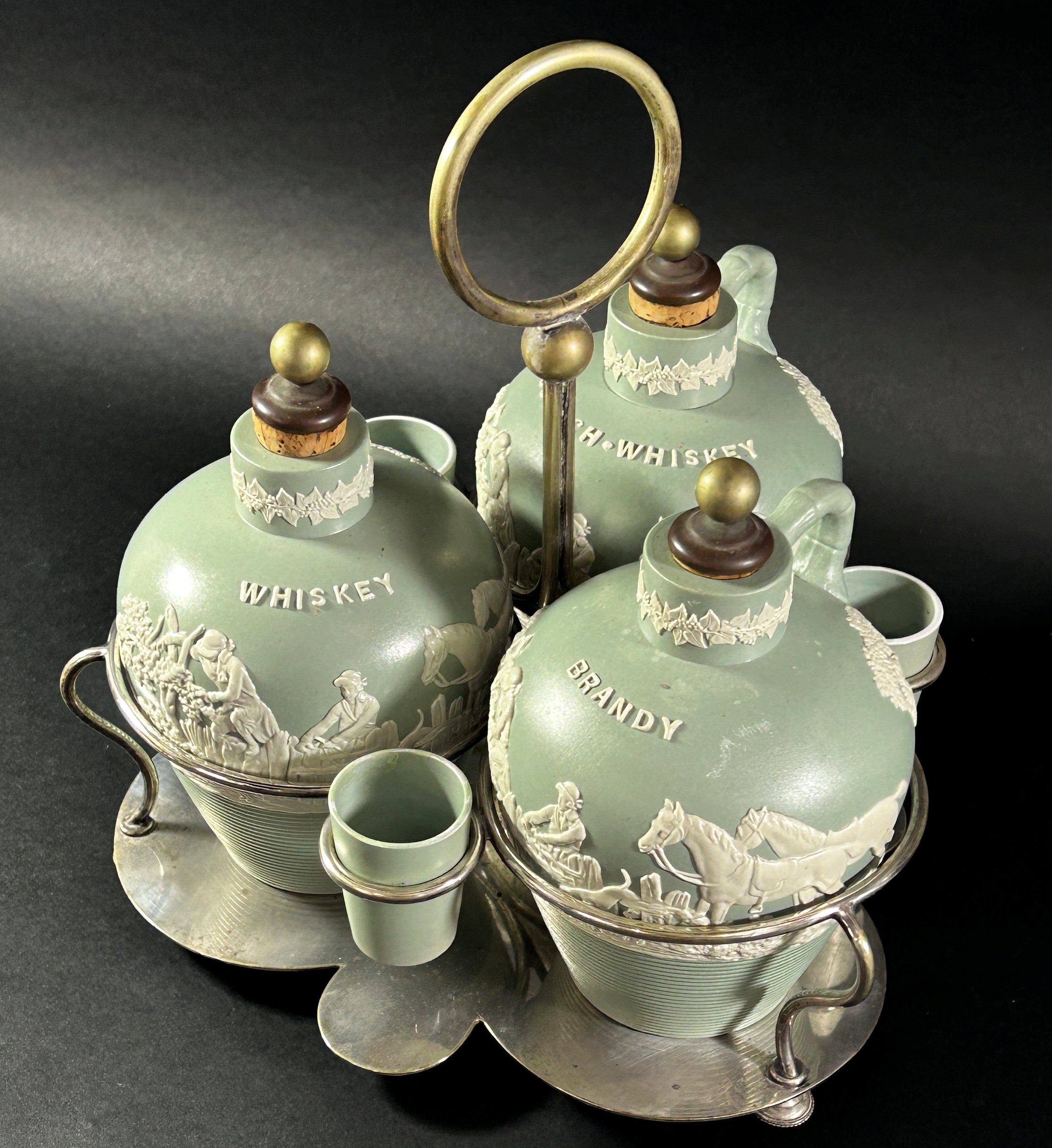 A late 19th century three bottle tantalus ceramics and silver plate frame, supporting three