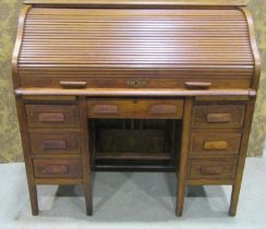 A medium oak kneehole twin pedestal roll top desk, the tambour roll enclosing a simply fitted