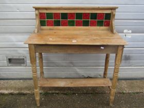 A Victorian stripped and waxed pine wash stand of simple form with turned supports and tiled back