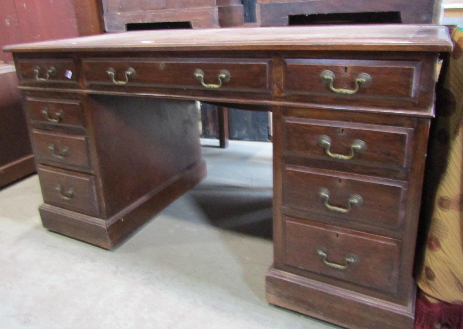 A Victorian oak kneehole twin pedestal desk with inset leather top over an arrangement of nine