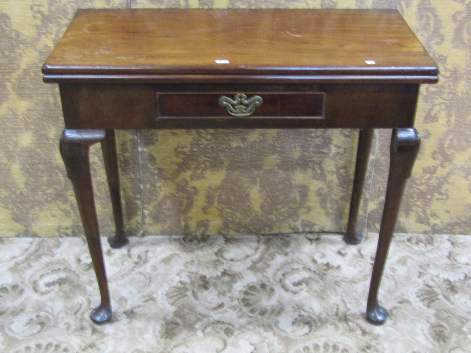 A Georgian mahogany rectangular fold over top tea table with central frieze drawer raised on