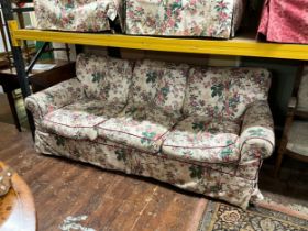 A three seat sofa by George Smith with rolled arms, with chinoiserie loose covers on turned supports