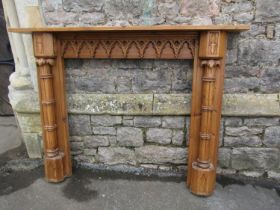 A contemporary stripped pine Gothic style fire surround labelled verso 111 cm high, the mantle 150