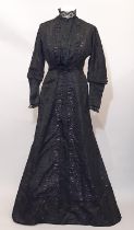 Circa 1910 full length ladies dress in black damask silk with purple highlights with front fastening