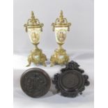A pair of brass urn shaped clock garnitures with a romantic pastoral scene, a circular tavern