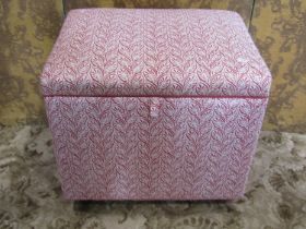 A rectangular upholstered box ottoman with hinged lid, covered throughout in repeating scrolling