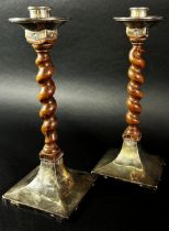 A pair of early 20th century English Arts & Crafts oak barley twist candlesticks with silver sconces