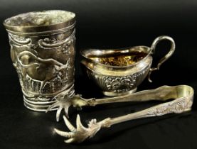 A small silver cream jug, a silver bird claw sugar tong and a Dutch? beaker with a dairy farm scene,