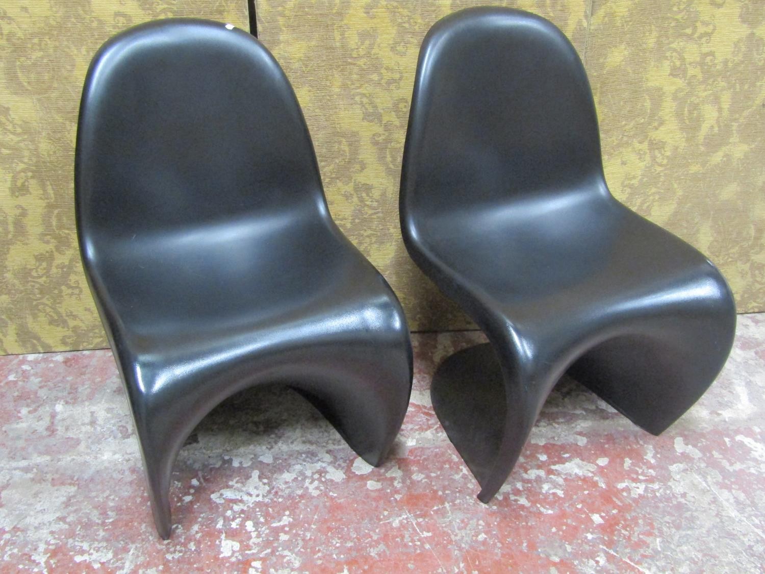 A pair of contemporary moulded plastic cantilever chairs in a black colourway in stacking format