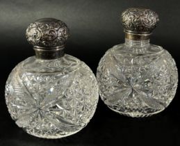 A pair of cut glass dressing table bottles with silver floral engraved caps