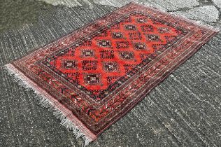 A old Hamadan carpet with a central panel of hooked medallions on a red brick ground, 200cm x 130cm.