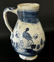 An 18th century tin glazed jug depicting to one side a bird, to the other a castle