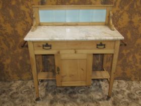 An Edwardian stripped pine marble top washstand with tiled splashback over a frieze drawer and