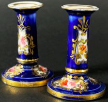 A miniature pair of Coalport candlesticks decorated with hand painted sprays of flowers and