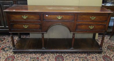 A Georgian country made dresser of five frieze drawers around a central arch and pot board, raised