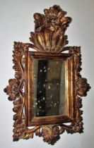 A small decorative gilt-framed wall mirror with pierced scrolling frame and floral surmount, 63 x