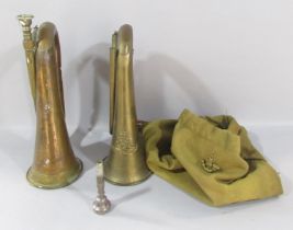 Two British Military brass bugles (as found), with a cloth bag and a cap badge.