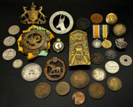 A collection of WWI regimental cap badges mainly commonwealth, together with a small number of coins