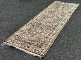 A faded wool Kazak type runner with four interlocking medallions in pink and yellow tones, 270cm x