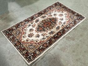 A modern machine made Persian style carpet in pink and brown tone on a cream ground, 180cm x 90cm