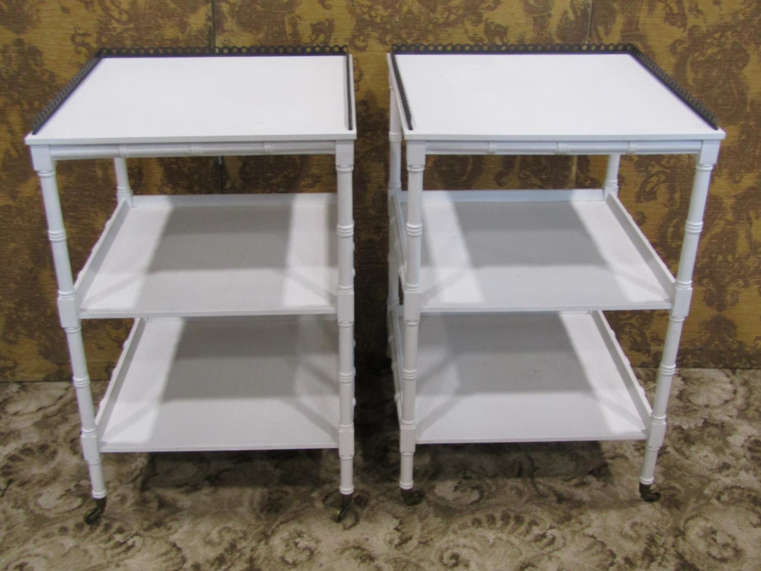 A pair of white painted Regency style three tier faux bamboo lamp tables, with pierced brass gallery