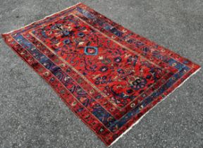 An old Hamadan woven wool rug, with floral patterns on a predominantly red ground, 190cm x 120cm