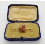 Yellow metal bar brooch set with a floral cluster of rubies, 4.2cm W approx, 3.1g, contained in a