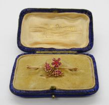 Yellow metal bar brooch set with a floral cluster of rubies, 4.2cm W approx, 3.1g, contained in a