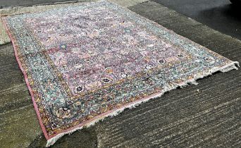 A large Persian design carpet with an all over floral pattern on a pink ground, 350cm x 250cm.