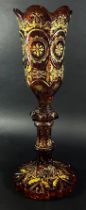 A 19th century tall Bohemian Gothic amber decorated glass vase, with a curved crenellated rim raised