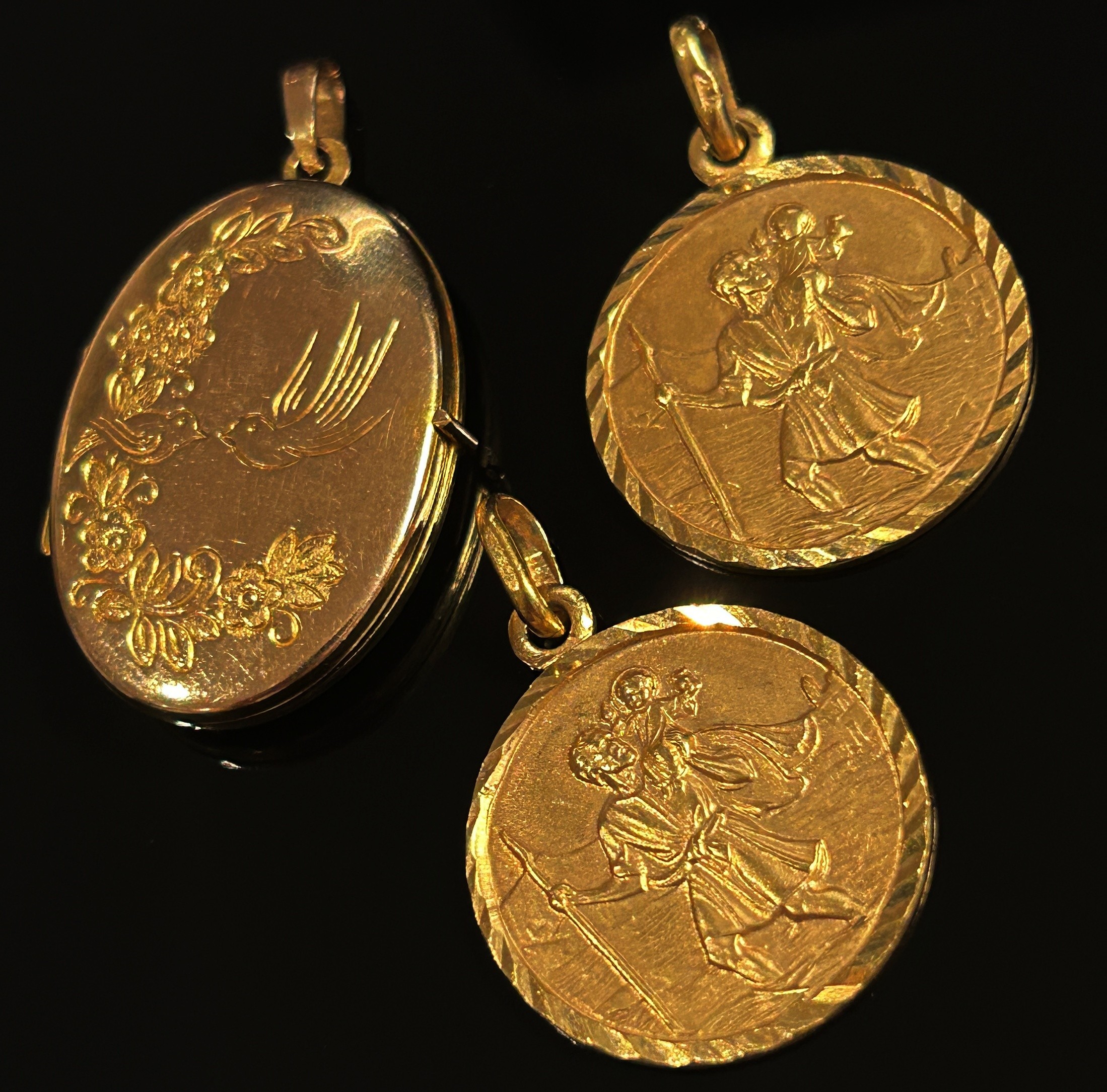 Three 9ct pendants; two St Christopher examples and a locket with engraved decoration, 9.4g total (
