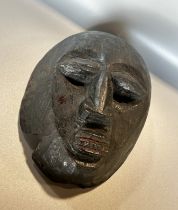 A small carved African hardwood mask, believed to be early 20th century or earlier, with remnants of