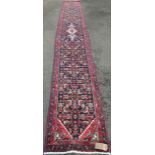 A Persian Sarouk runner full pile with rich red and blue pattern, 500cm x 66cm