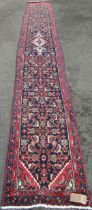 A Persian Sarouk runner full pile with rich red and blue pattern, 500cm x 66cm