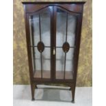 An inlaid Edwardian mahogany display cabinet enclosed by a pair of three quarter arched glazed and