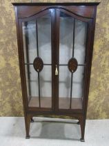 An inlaid Edwardian mahogany display cabinet enclosed by a pair of three quarter arched glazed and