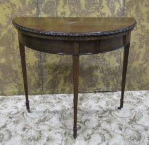 An Edwardian mahogany demi-lune fold over top card table in the Georgian style raised on square