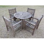A weathered circular teak table and four associated armchairs (5)