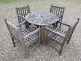 A weathered circular teak table and four associated armchairs (5)