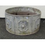 A weathered circular lead planter with repeating lions mask relief panels, 32 cm high x 60 cm