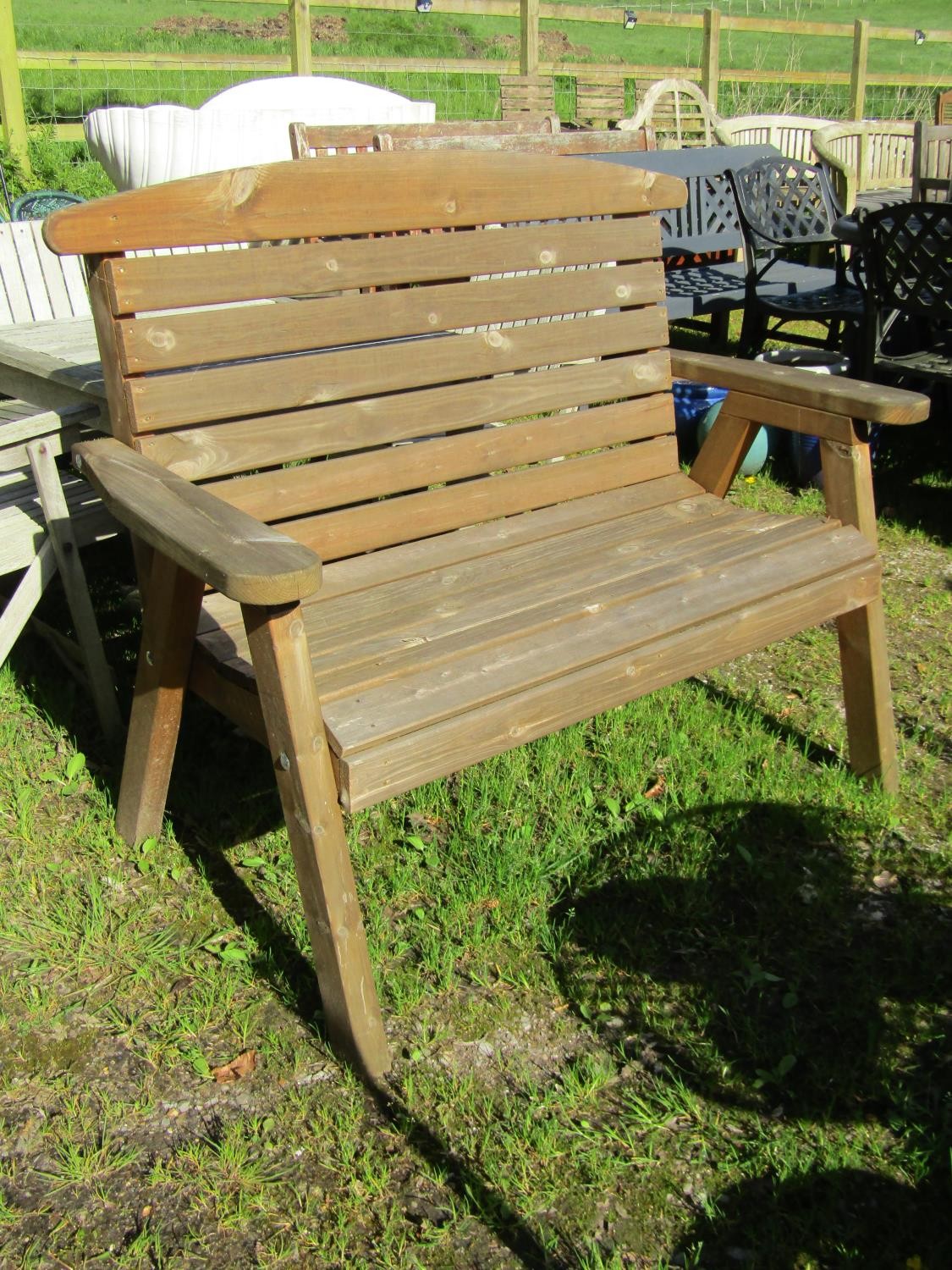 A contemporary weathered softwood 2 seat garden bench with slatted seat and back raised on splayed