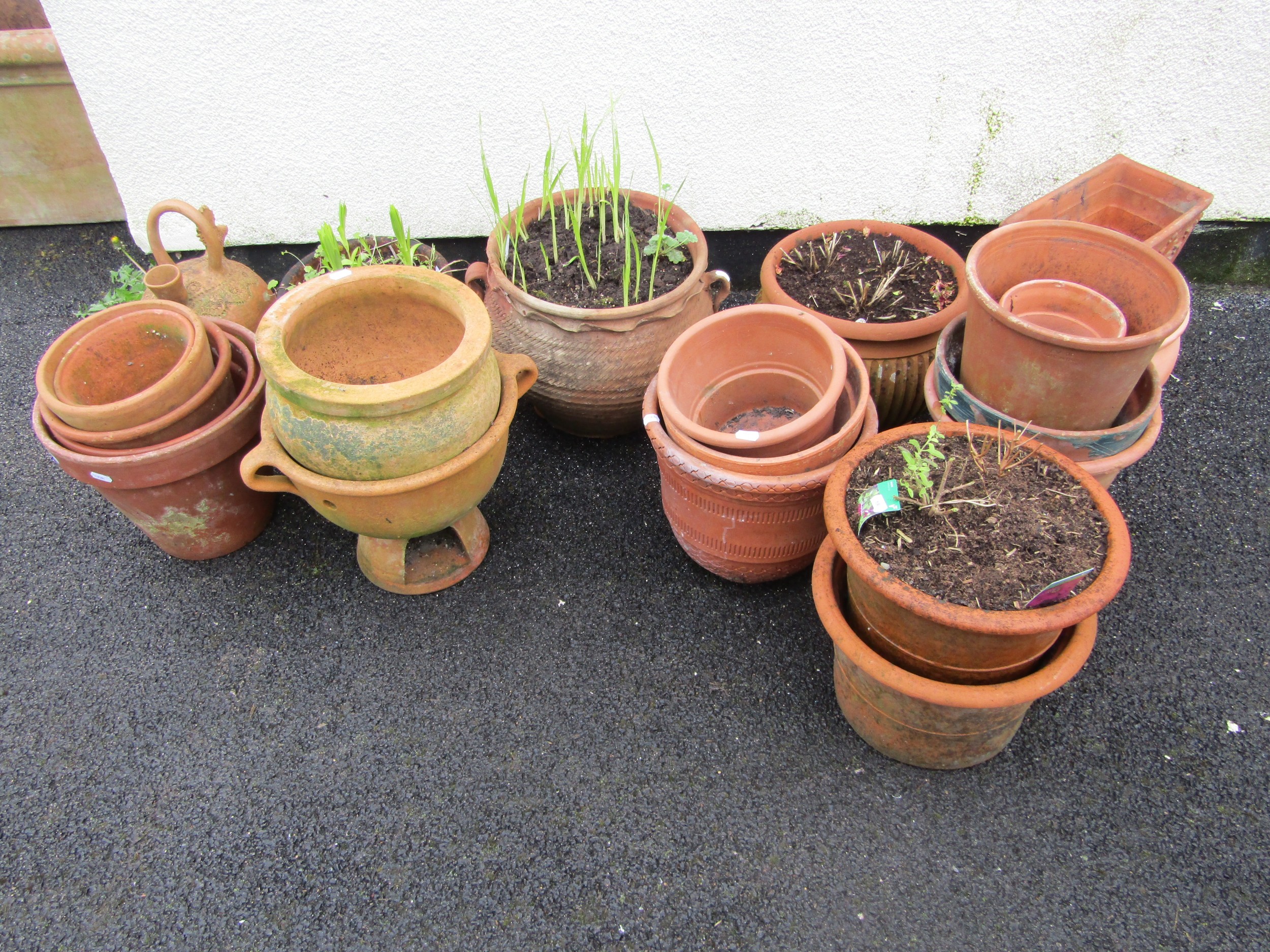 A quantity of weathered terracotta flower pots and planters of varying size and design including a