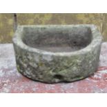 A weathered D shaped natural stone trough with drainage hole