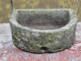 A weathered D shaped natural stone trough with drainage hole