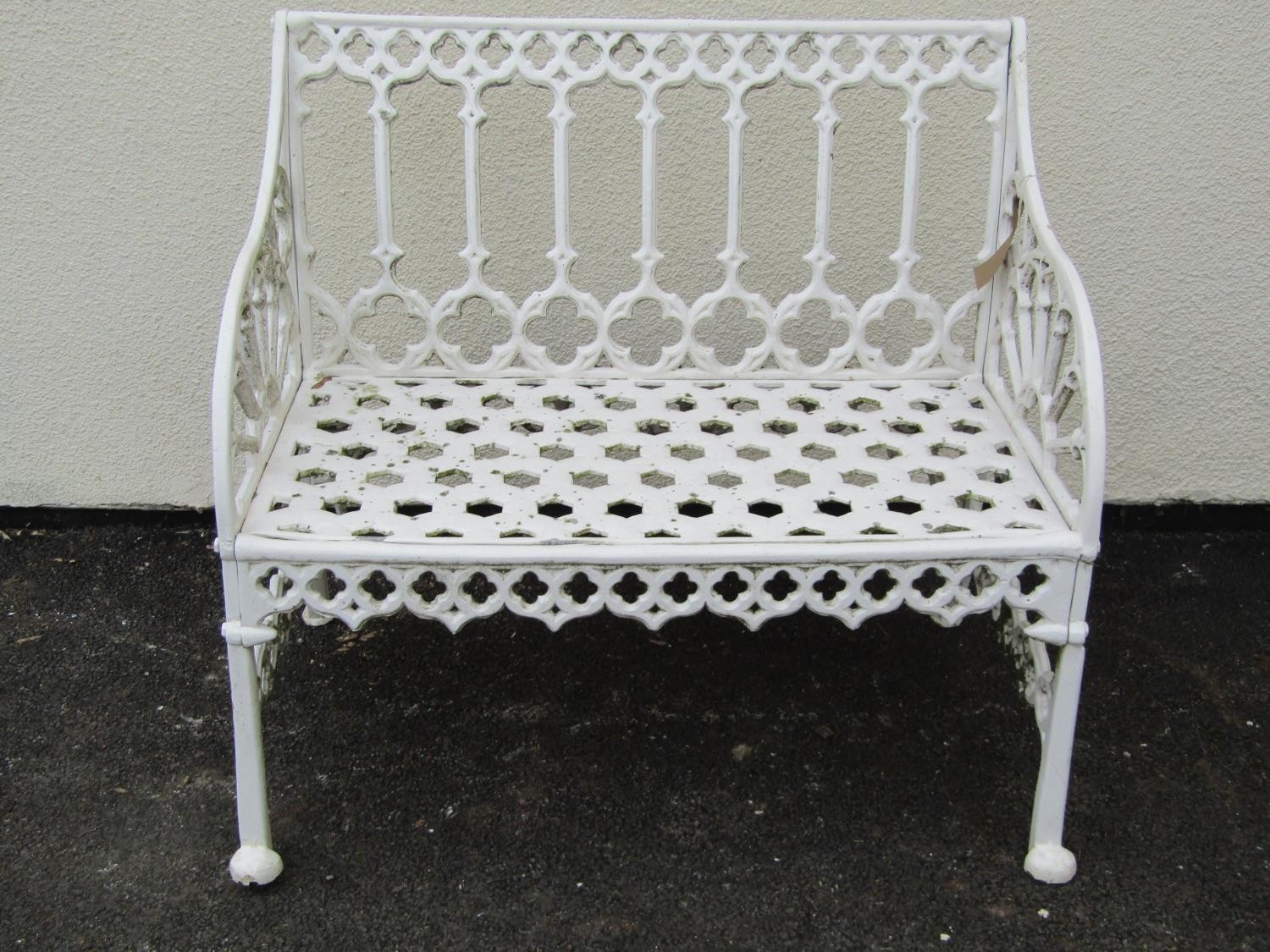 A small cream painted cast alloy two seat garden bench with pierced gothic tracery detail, 87 cm,