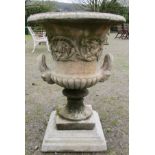 A large cast composition stone campana shaped garden urn with repeating scrolling foliate relief