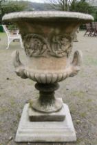 A large cast composition stone campana shaped garden urn with repeating scrolling foliate relief